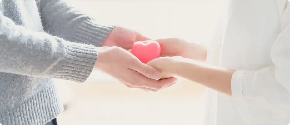 ハート形のオブジェクトを手渡す夫婦の手