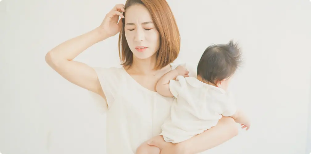 頭を抱える女性と抱っこされた赤ちゃん